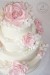 Svatební dort v krémové barvě s krajkou, růžemi a fréziemi.